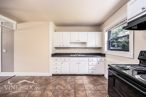 A kitchen with a black stove top oven and white cabinets.
