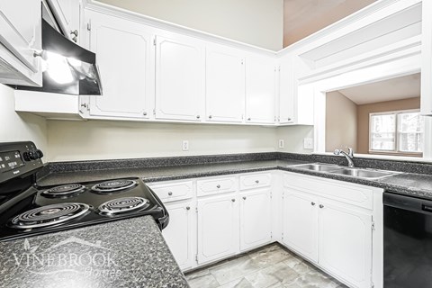 A kitchen with white cabinets and a black stove top.