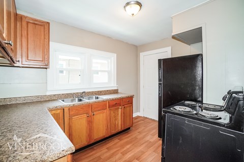 A kitchen with wooden cabinets and a black refrigerator.