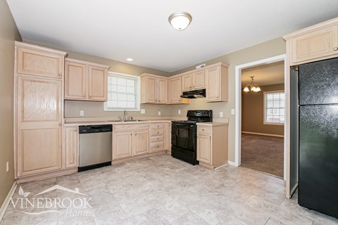 A kitchen with wooden cabinets and a black refrigerator.