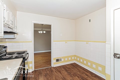 A kitchen with a stove top oven and a doorway leading to a hallway.