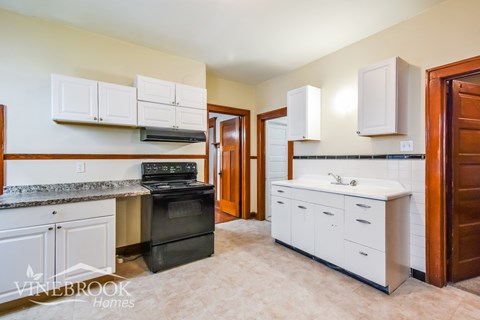 A kitchen with white cabinets and a black stove top oven.