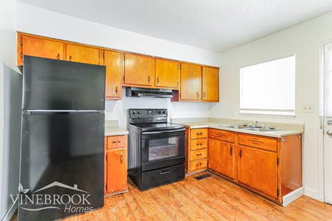 A kitchen with wooden cabinets and a black refrigerator.