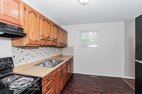 A kitchen with wooden cabinets and a black stove top oven.