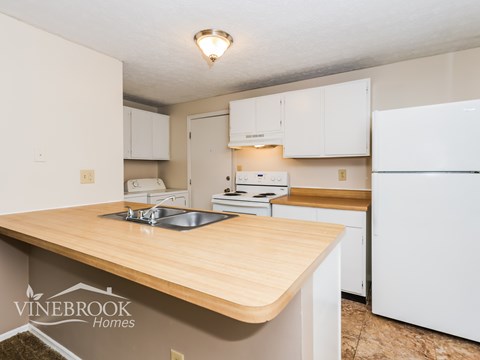 A kitchen with a wooden counter top and white appliances.