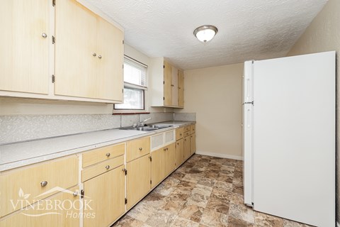 A kitchen with a white refrigerator and wooden cabinets.