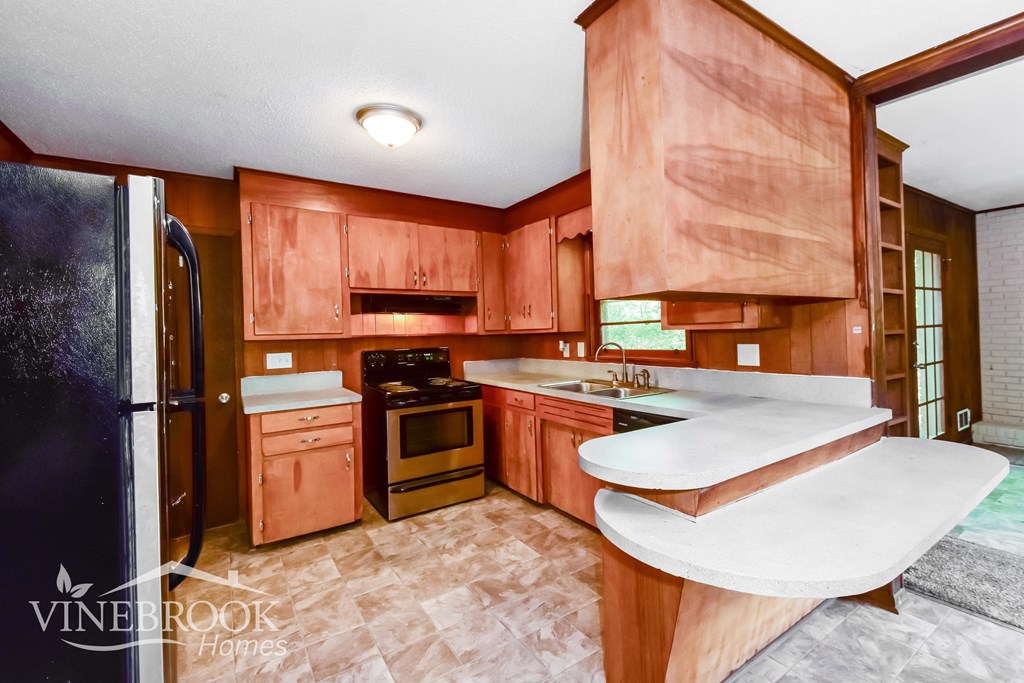 A kitchen with wooden cabinets and a black refrigerator.
