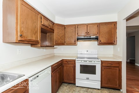 A kitchen with wooden cabinets and a white stove top oven.