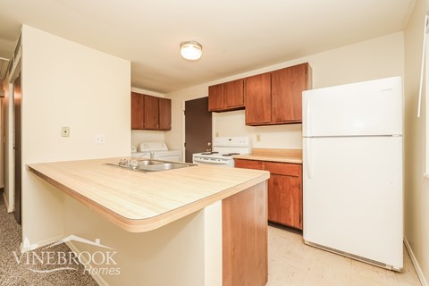 A kitchen with a white refrigerator and wooden cabinets.