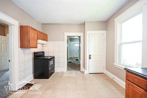 A kitchen with a black stove top oven and white tiled walls.