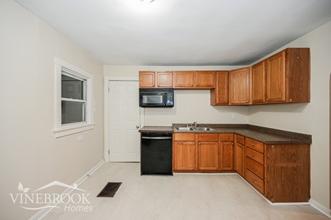 A kitchen with wooden cabinets and a black dishwasher.