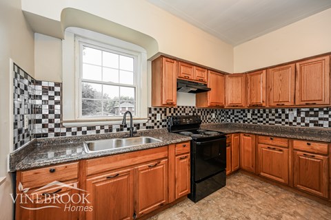 A kitchen with wooden cabinets and black and white checkered backsplash.