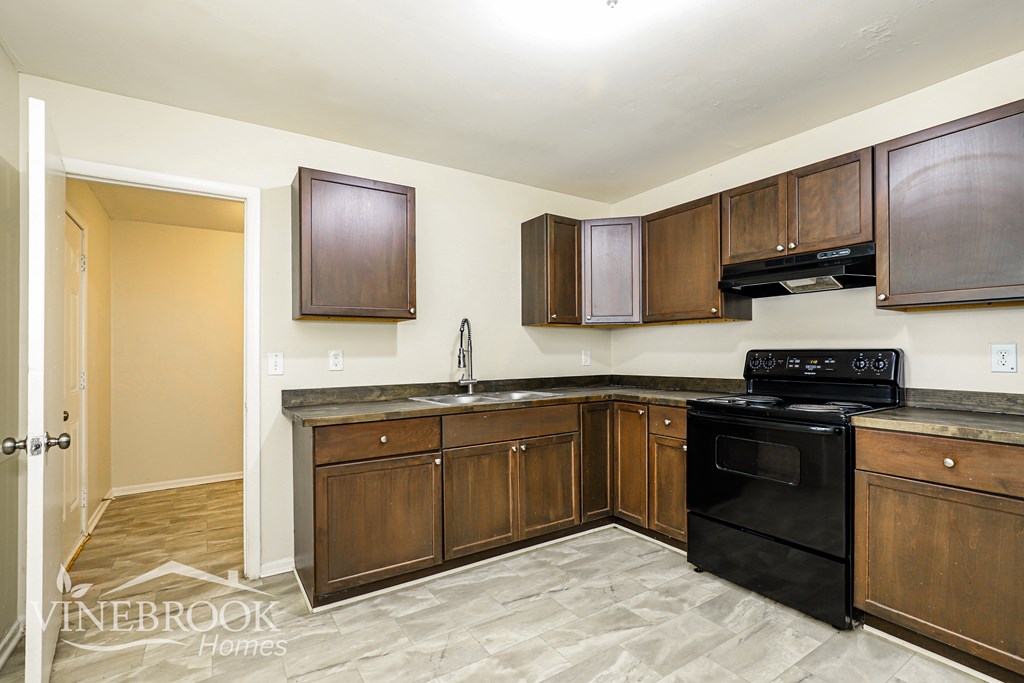 A kitchen with a black stove top oven and wooden cabinets.