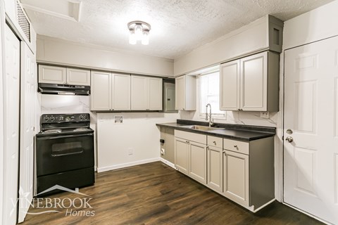 A kitchen with a black oven and cabinets.