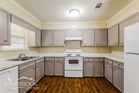 A kitchen with wooden floors and white appliances.