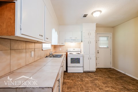 A kitchen with white cabinets and a Vinebrook Homes logo.