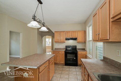 A kitchen with a black stove top oven and wooden cabinets.