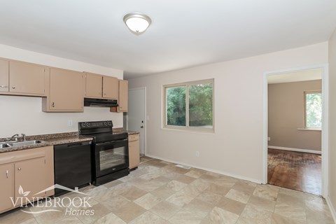 A kitchen with beige cabinets and a black oven.
