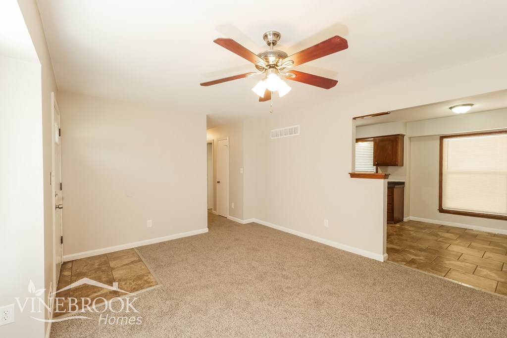 A room with a ceiling fan and carpeted floor.
