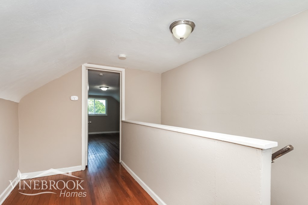 the upstairs landing of a renovated home with a hallway and a door to a room
