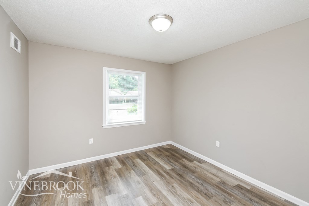 a bedroom with wood flooring and a window
