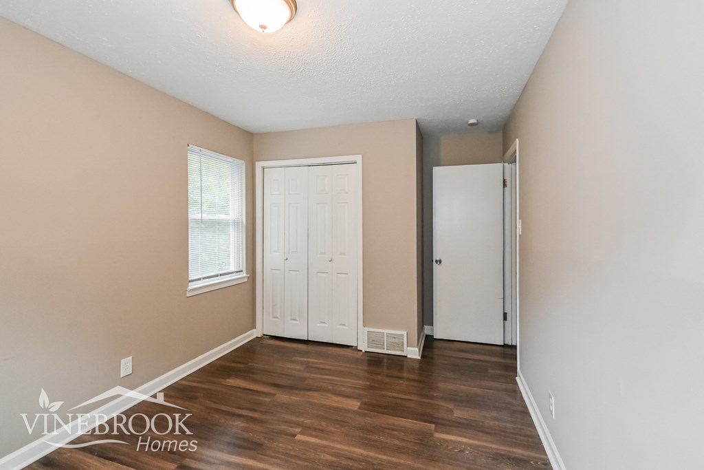 the living room of an apartment with a hard wood floor and a white door