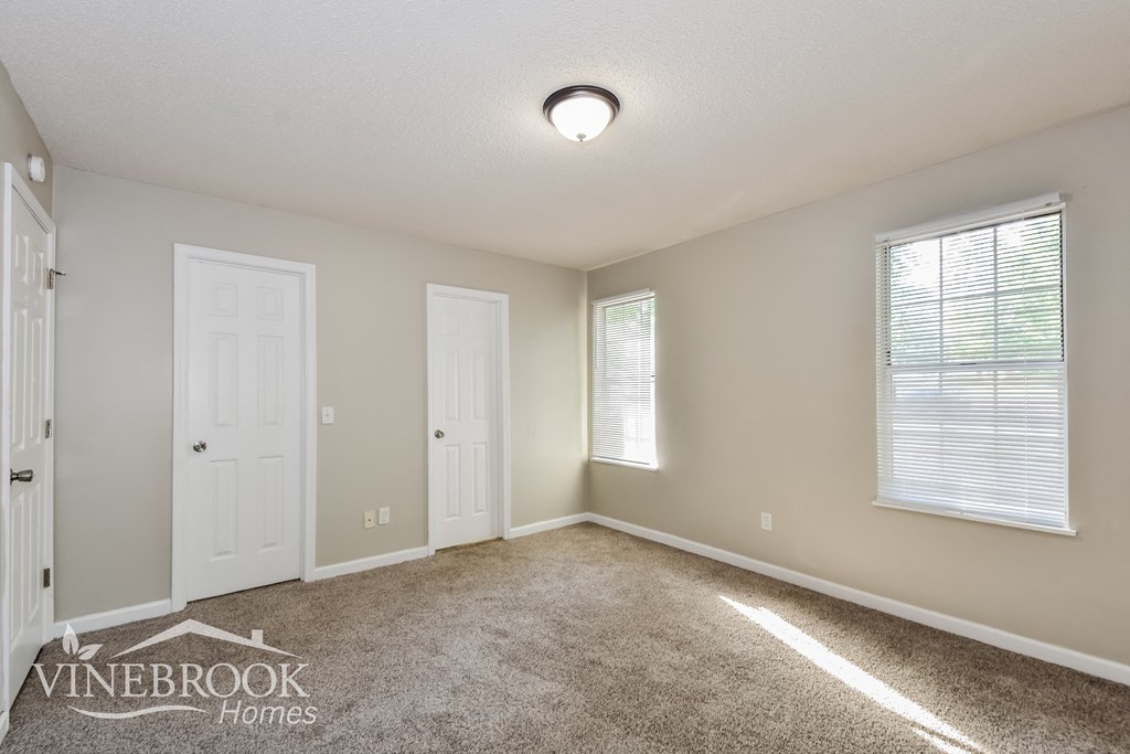 a bedroom with a carpeted floor and two doors and a window