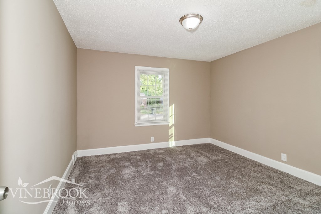a bedroom with a carpeted floor and a window