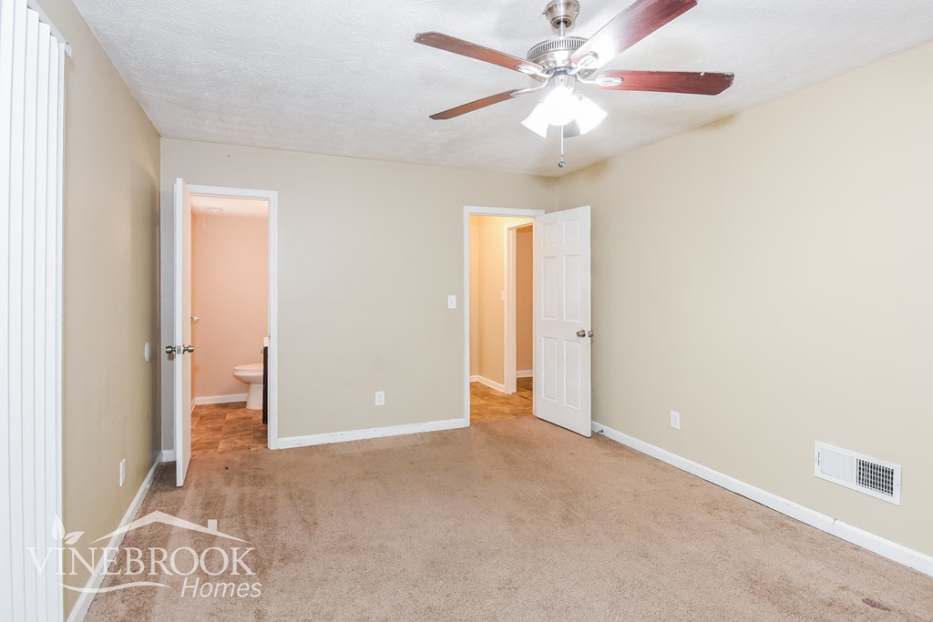 a living room with carpet and a ceiling fan