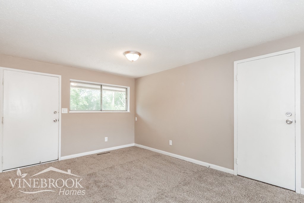 a bedroom with carpet and two doors and a window