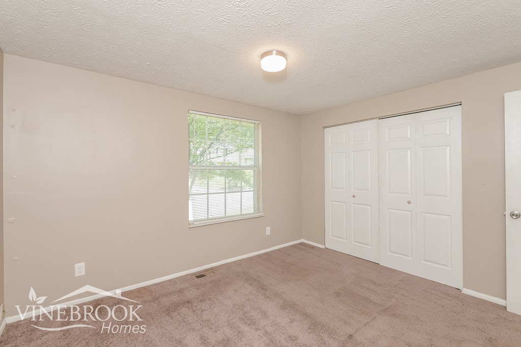 a bedroom with a carpeted floor and a white door