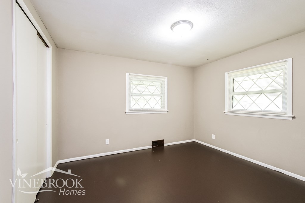a room with a dark floor and two windows