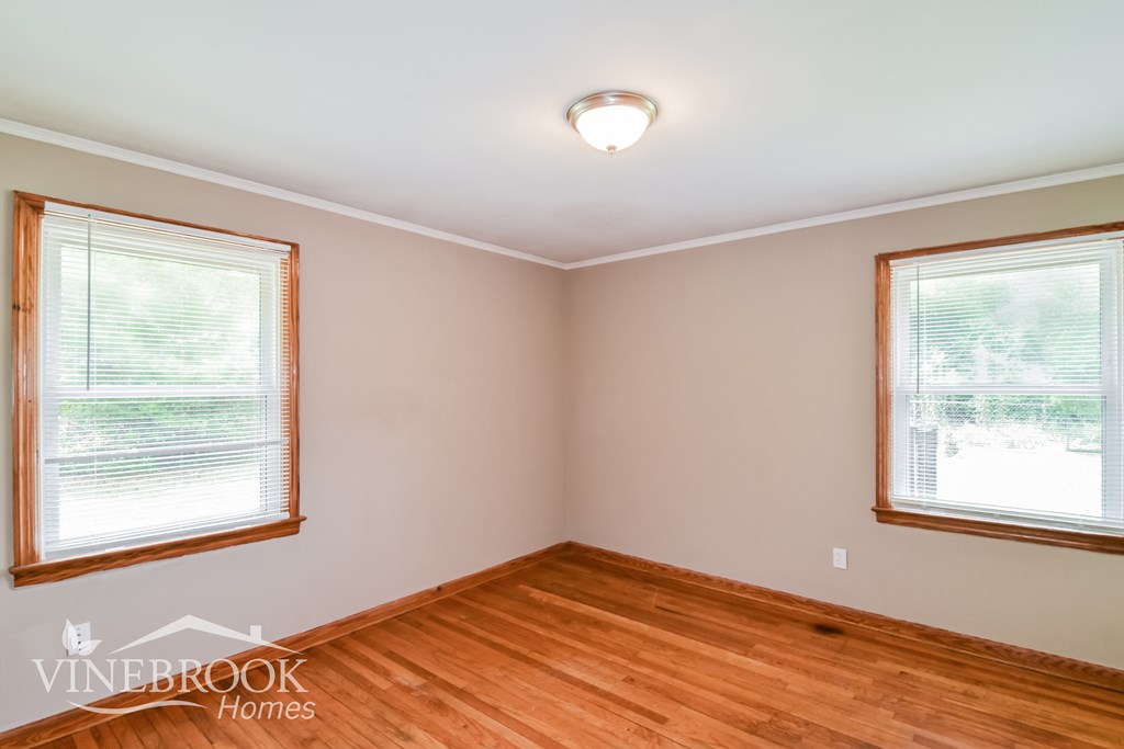 the living room of a house with wood floors and two windows