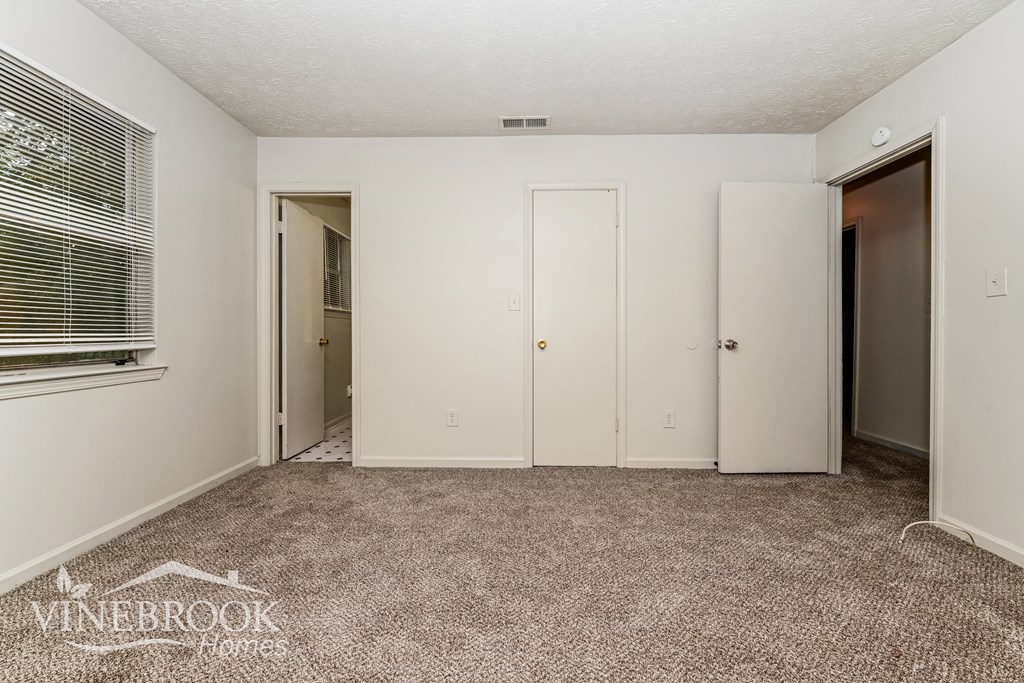a bedroom with a carpeted floor and a door to a closet