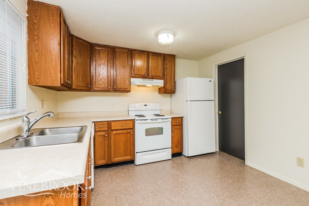 A kitchen with wooden cabinets and white appliances.