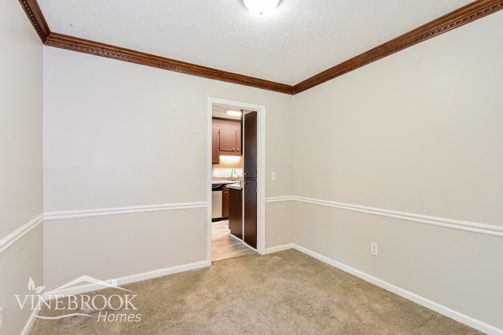 a living room with a carpet and a door to a bathroom