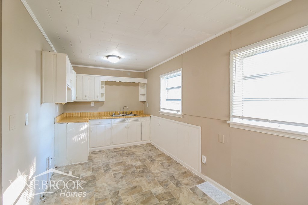 a kitchen with white cabinets and a counter top and a sink