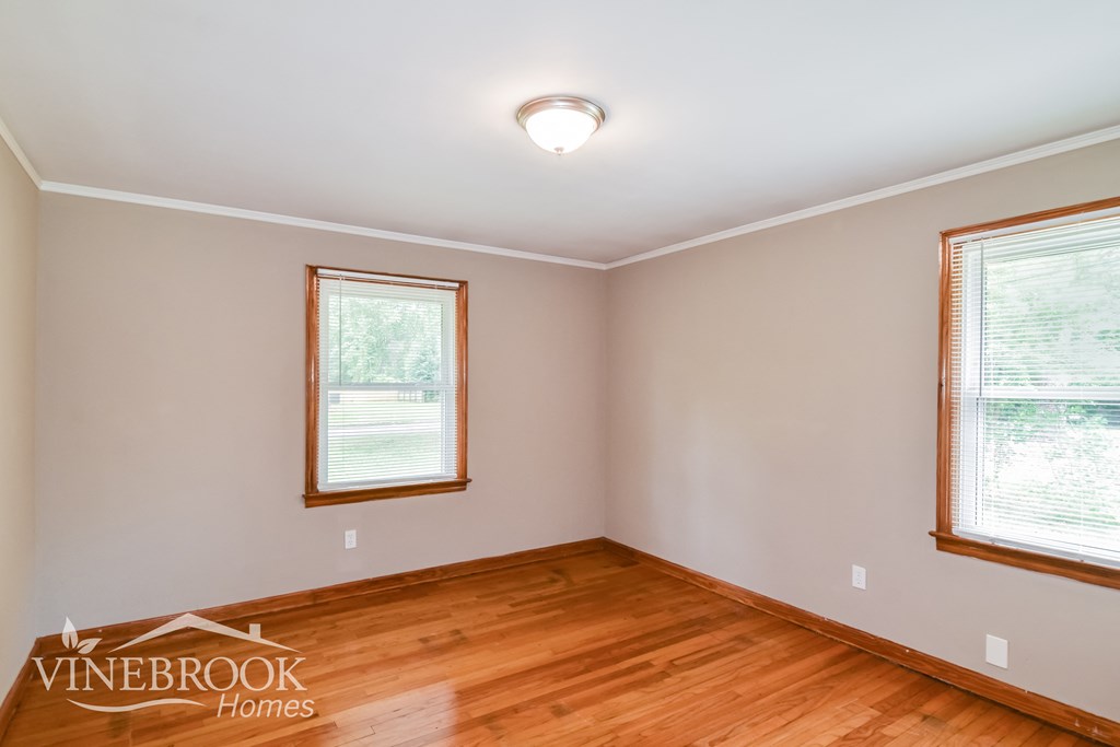 the living room of a house with wood floors and two windows