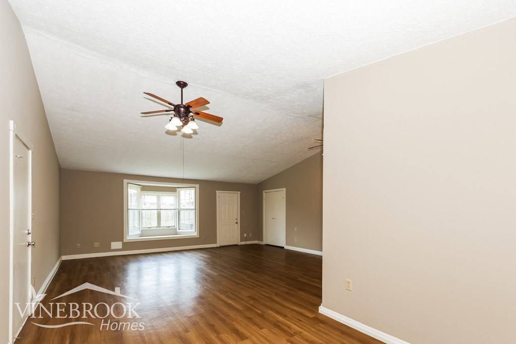 an empty living room with a ceiling fan and wood floors