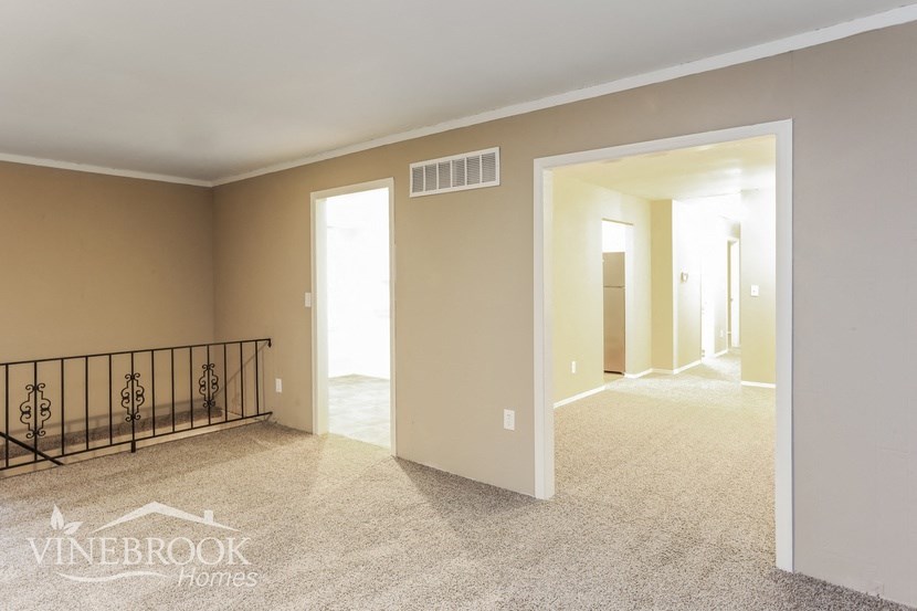 an empty living room with a balcony and a hall way
