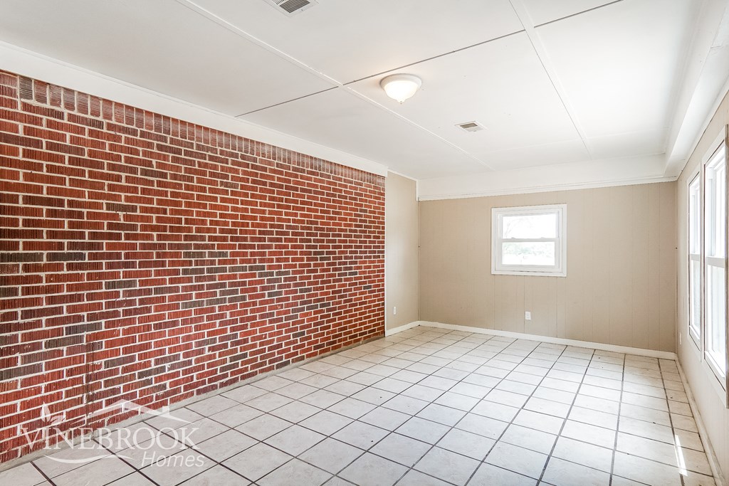 an empty room with a brick wall and a window
