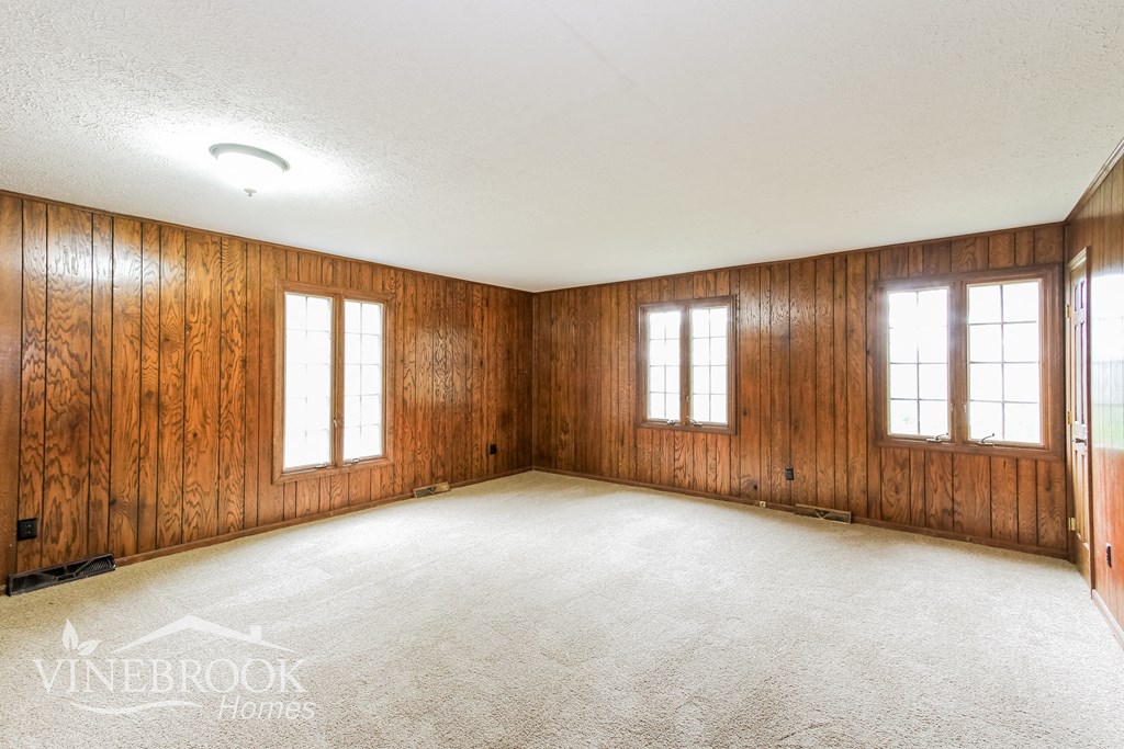 an empty room with a carpeted floor and three windows