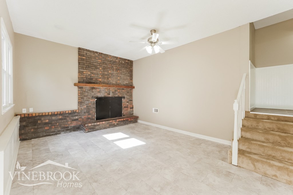 a living room with a fireplace and a tile floor and a staircase