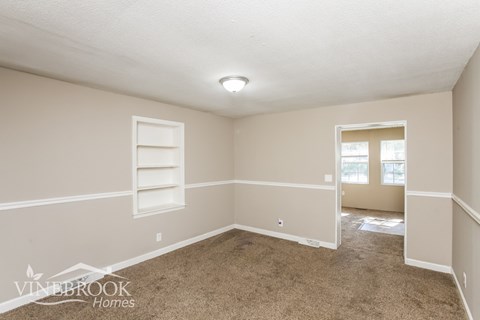 a living room with carpet and a window and white shelves