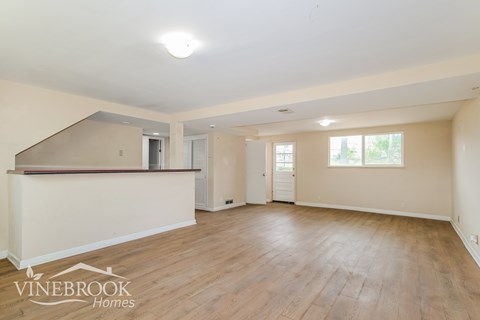 A spacious room with wooden flooring and a Vinebrook Homes logo.