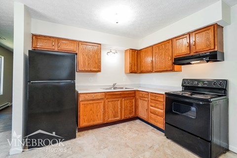 a kitchen with black appliances and wooden cabinets and a black refrigerator