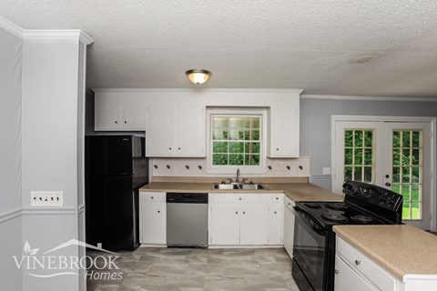 a white kitchen with black appliances and white cabinets