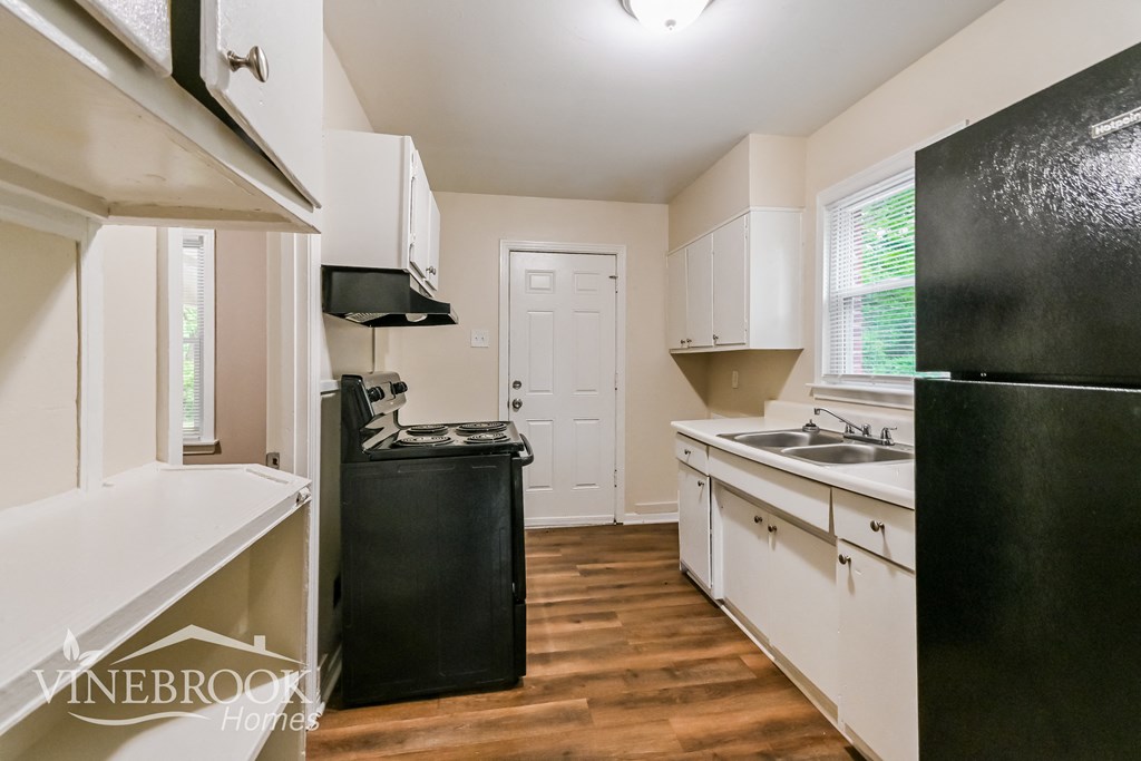 a kitchen with white cabinets and black appliances and a black refrigerator