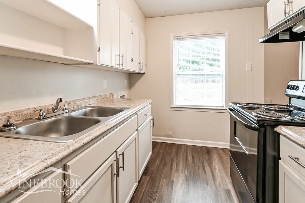 a kitchen with white cabinets and granite counter tops and a sink