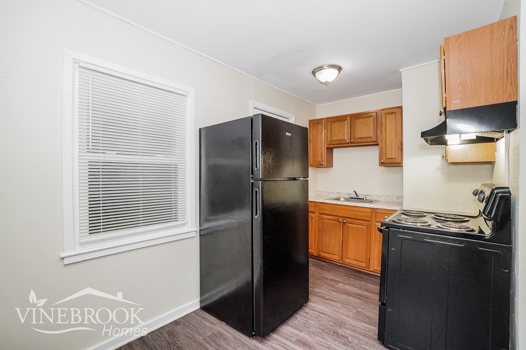 a kitchen with black appliances and wooden cabinets and a window